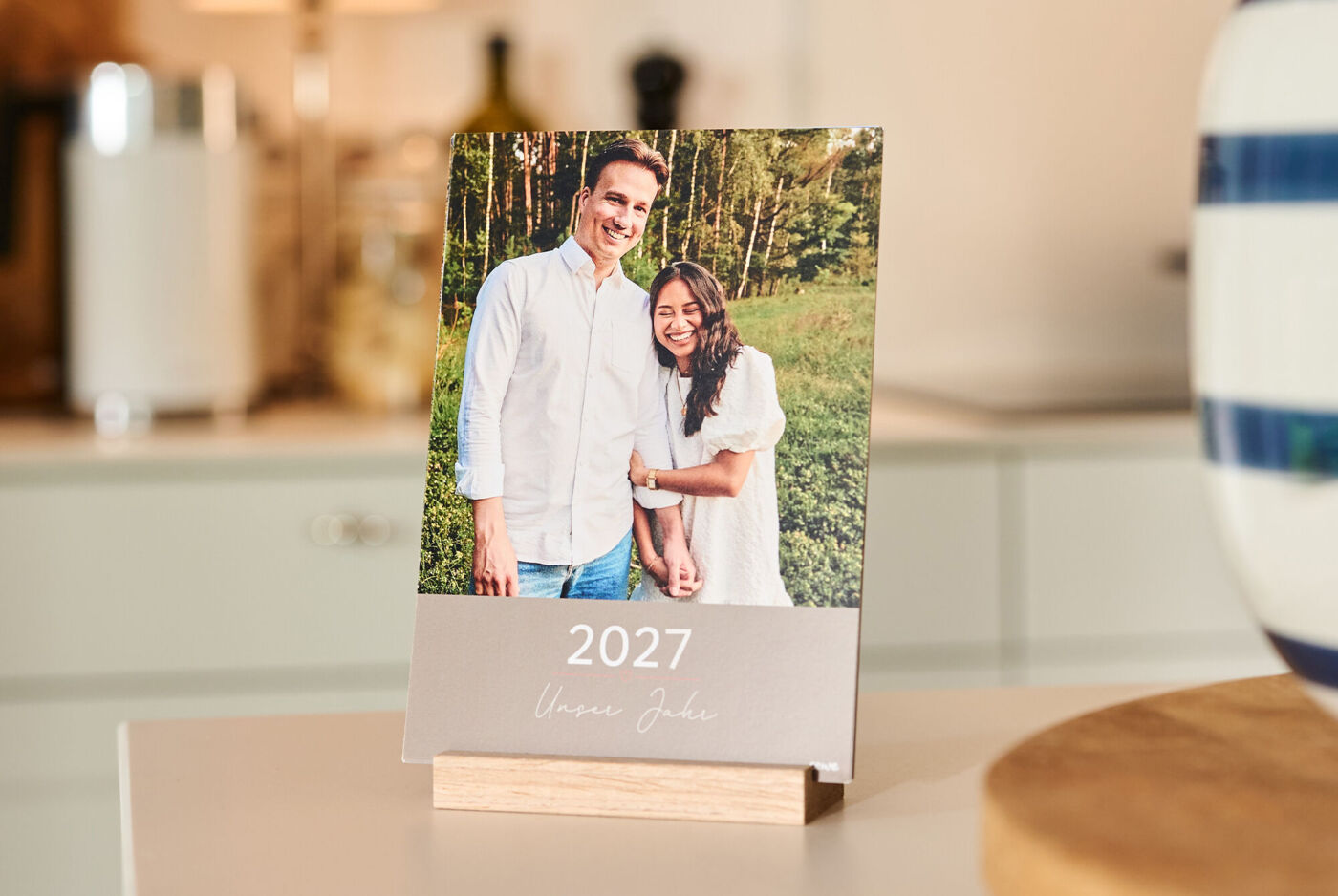 CEWE Tischkalender 2027 mit Paarfoto und dem Schriftzug „Unser Jahr“ auf einem Holzständer