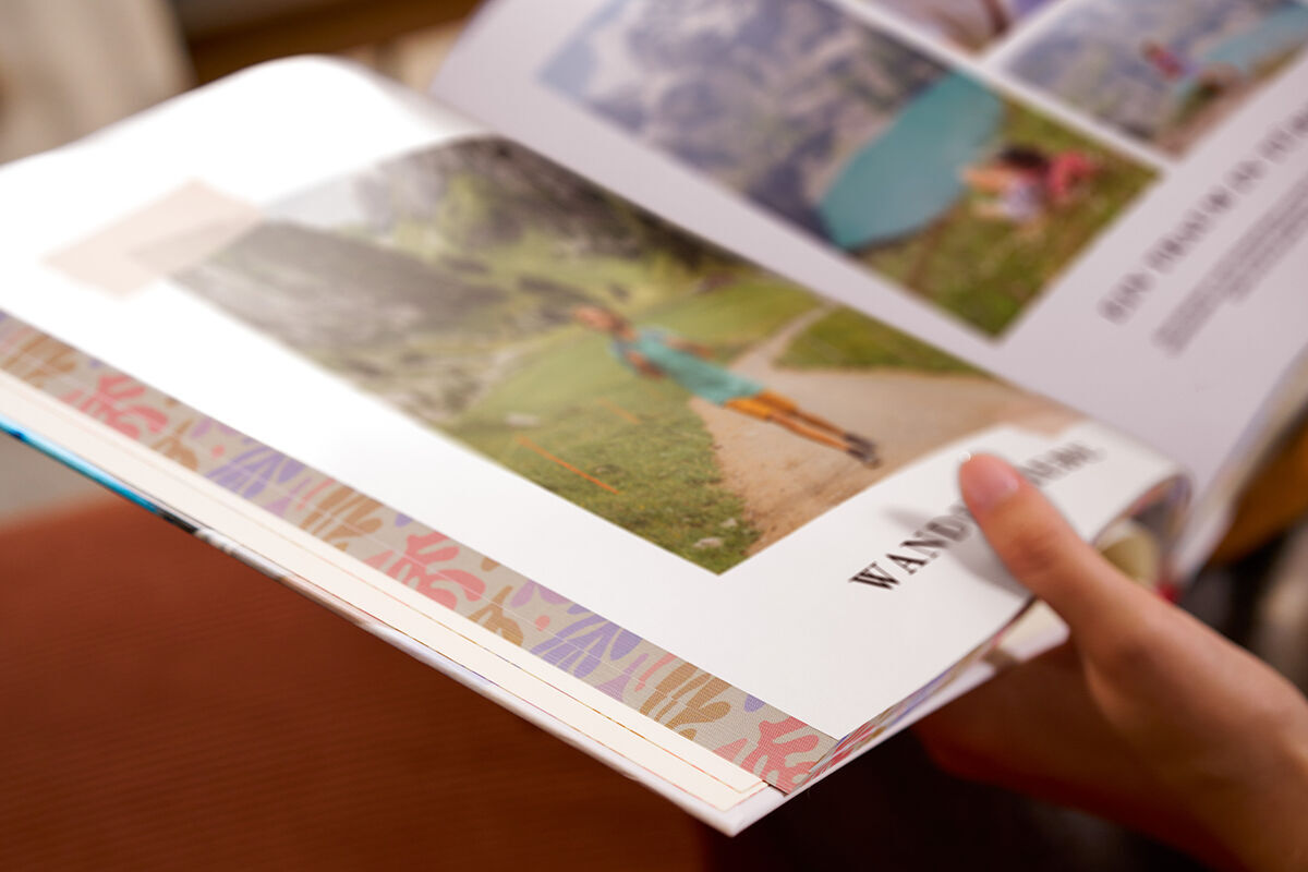Es ist eine Nahaufnahme von einem aufgeschlagenen CEWE FOTOBUCH mit Farbschnitt zu sehen.