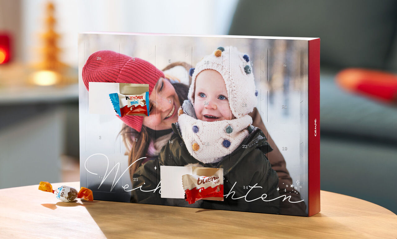 CEWE Adventskalender mit Winterfoto und zwei geöffneten Türchen, in denen sich Produkte von kinder befinden.